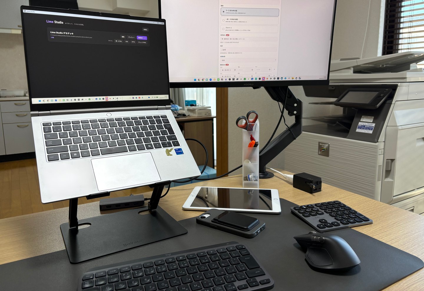 ケアサポート デイズの執務デスク。ノートPCと外部モニターに、記録や日程調整に使う自作アプリを表示している